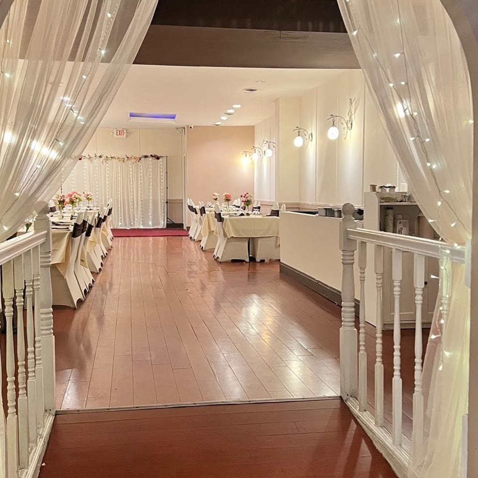 Elegant Jalsa dining room with white draped tables, floral centerpieces, and string lights.