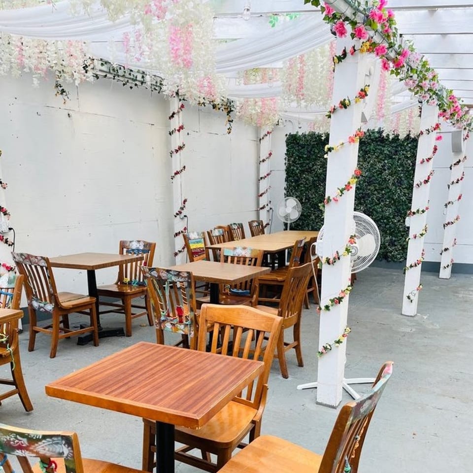 JALSA's outdoor patio with wooden tables and chairs, adorned with white and pink floral garlands.