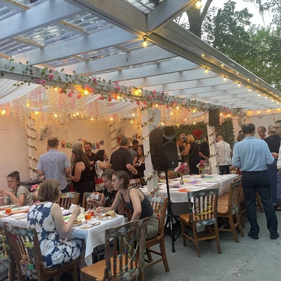 Guests mingle and dine under a string-lit, floral-decorated pergola at JALSA restaurant.